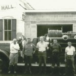 Antique photo of men standing in front of fire engine and fire hall